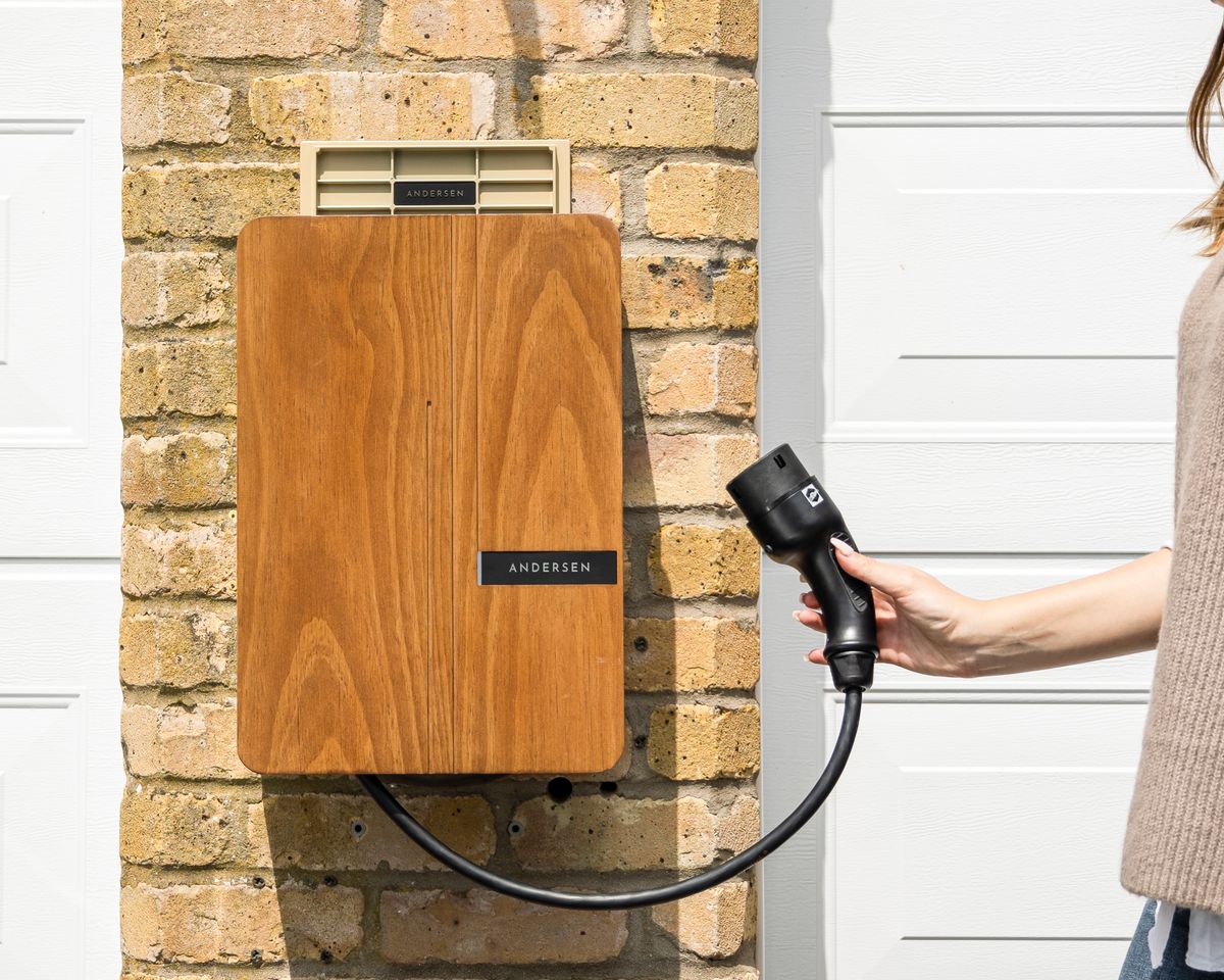 Wall-mounted home EV charger with a Type 2 connector on a brick wall